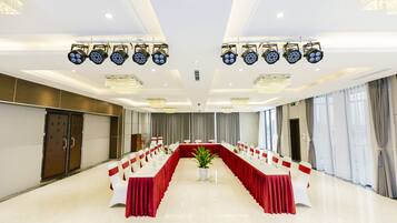 A conference room with a long table, white chairs, and red tablecloths.