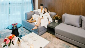 A modern living room with a large chandelier, grey sofas, and a coffee table with decorative items. - Songlam Waterfront Hotel - 藍江酒店 (Nghi Xuân)