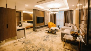 A modern living room with a sofa, a coffee table, a TV, and a small kitchen area. - Songlam Waterfront Hotel - 藍江酒店 (Nghi Xuân)