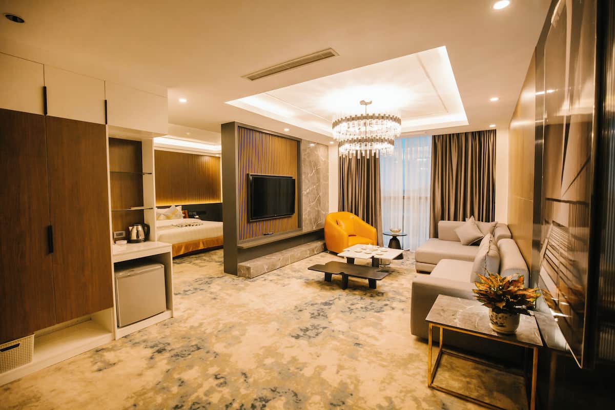 A modern living room with a sofa, a coffee table, a TV, and a small kitchen area.