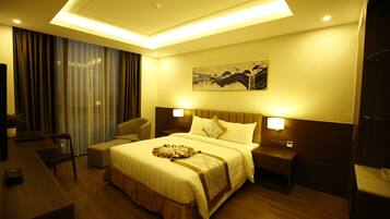 A hotel room with a large bed, bedside tables, a desk, and a chair.