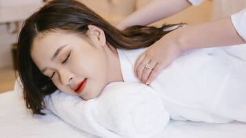 A person lying on a white textured surface, possibly a bed or massage table, with a white garment.