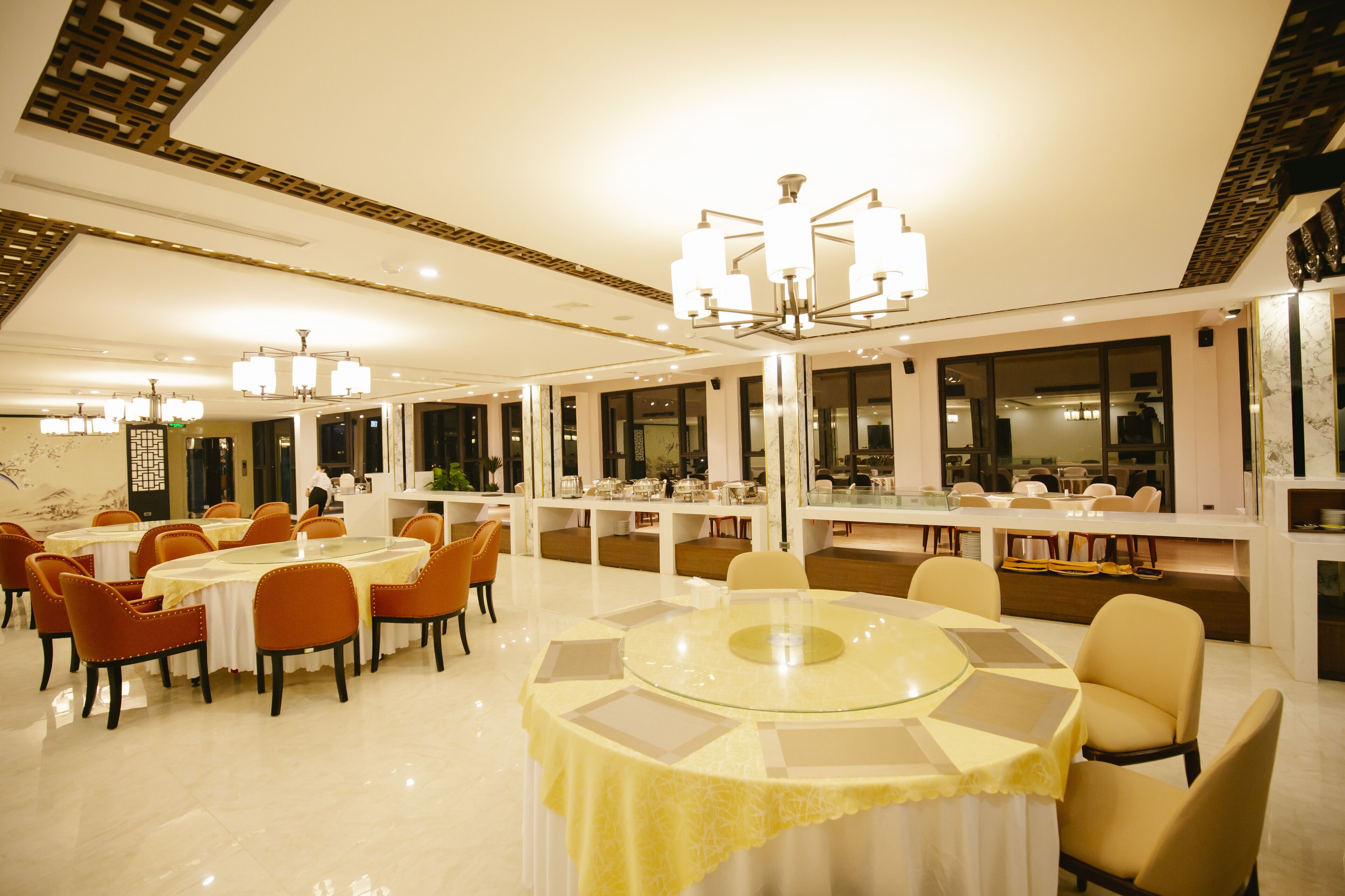 A modern dining area with round tables, orange chairs, and a central glass table.