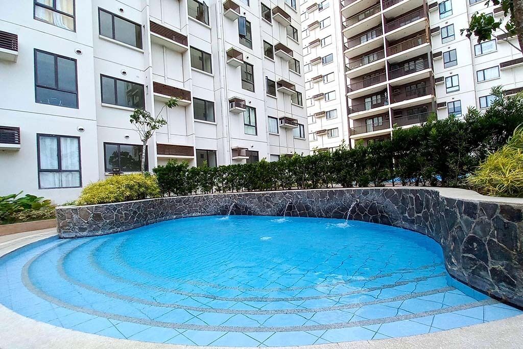 Edifici residencial amb piscina envoltat de vegetació.