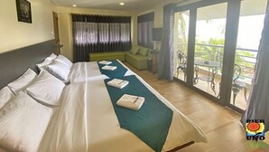A hotel room with a large bed, a sofa, and a balcony with outdoor furniture. - Pier Uno Dive Resort (Bauan)