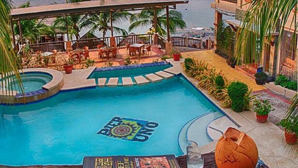 A pool area with a view of the ocean, outdoor seating, and a covered patio. - Pier Uno Dive Resort (Bauan)