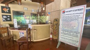 A reception area with a sign detailing safety guidelines, a counter, a chair, and a decorative fish tank. - Pier Uno Dive Resort (Bauan)