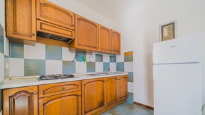 Una cocina con armarios de madera, estufa a gas, un lavamanos y un refrigerador blanco.