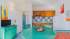 A compact kitchen with wooden cabinets, a dining table, and a TV on a cabinet. - APP.TI STELLA MARINA - STELLA MARINA 4 (Marina di Campo)