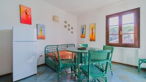 A room with a bed, a dining table with chairs, a refrigerator, and artwork on the walls. - APP.TI STELLA MARINA - STELLA MARINA 4 (Marina di Campo)