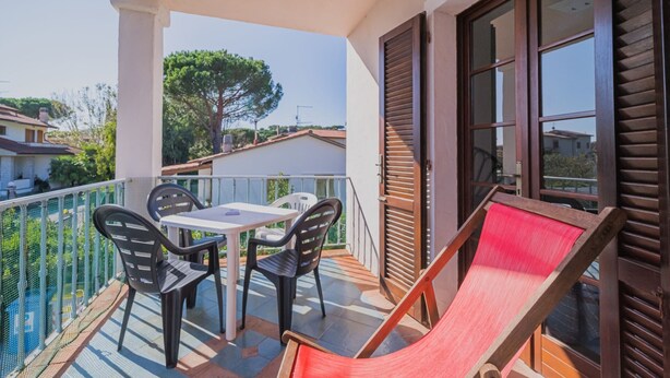 A balcony with a table and chairs, a hammock, and a view of the surrounding area. - APP.TI STELLA MARINA - STELLA MARINA 4 (Marina di Campo)