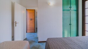 A hotel room with a bed, a wardrobe, and a door leading to another room. - APP.TI STELLA MARINA - STELLA MARINA 4 (Marina di Campo)