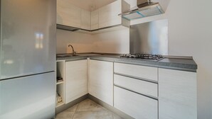 A modern kitchen with a stainless steel refrigerator, a gas stove, and light wood cabinetry.