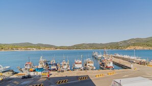 A harbor with multiple boats docked, a clear sky, and hills in the background.