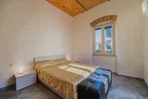 Una camera da letto con un letto, un comodino con una lampada, una finestra e vista sull'esterno.
