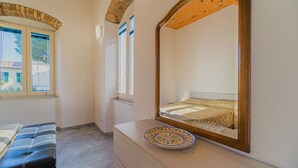 A bedroom with a bed, a dresser, a mirror, and a window.