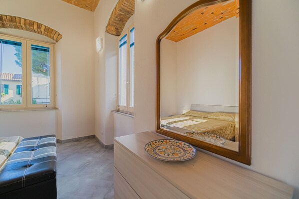 A bedroom with a bed, a dresser, a mirror, and a window.