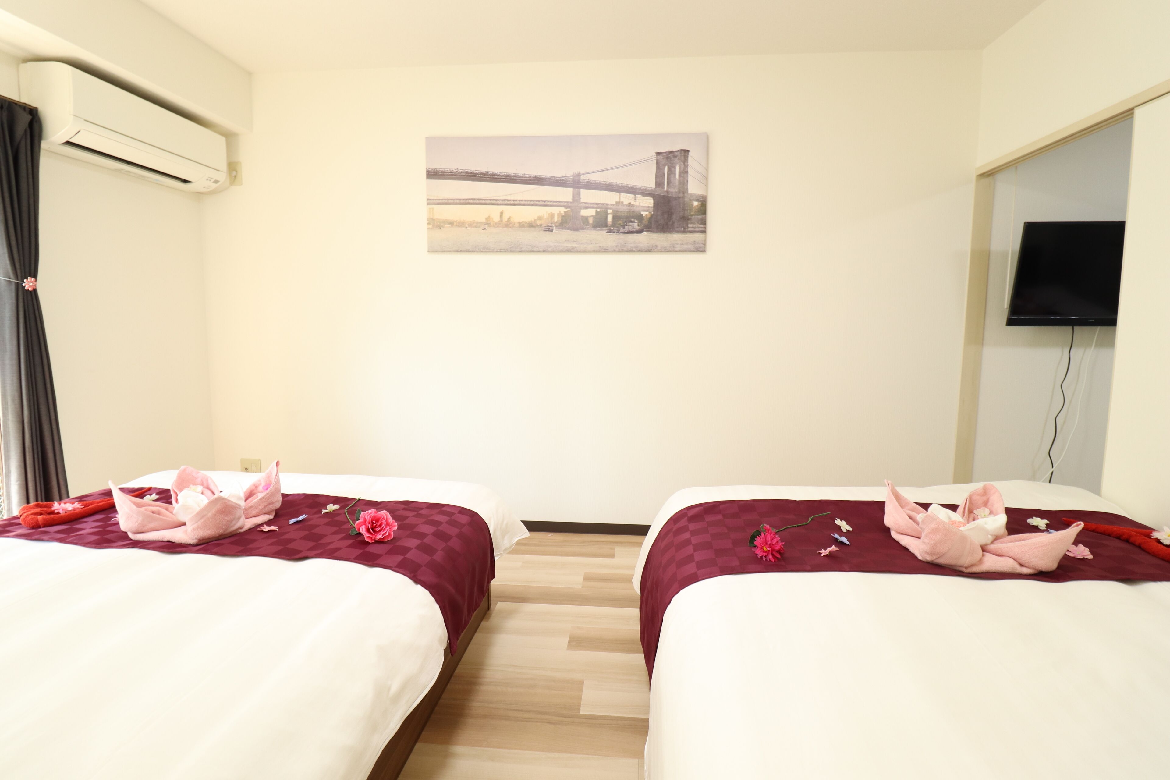 Une chambre d’hôtel avec deux lits, un tableau représentant un pont, un climatiseur et une télévision.