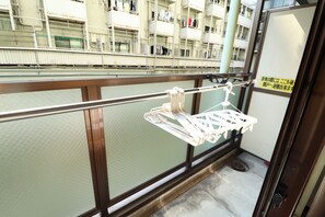A balcony with a metal railing and a white laundry basket hanging on it. - Koto Saiwaicho (Osaka)