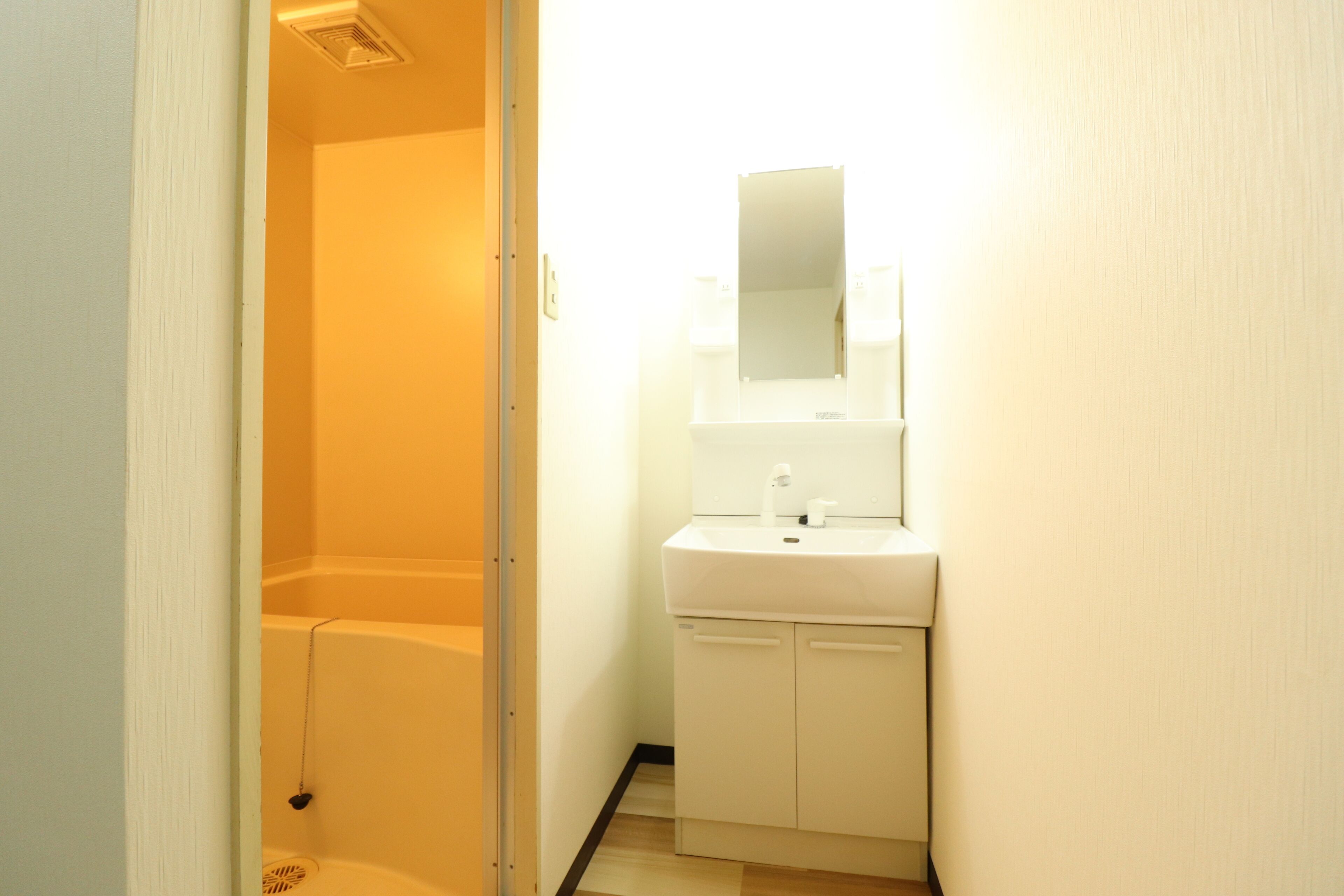 A small bathroom with a white sink, mirror, and shower.