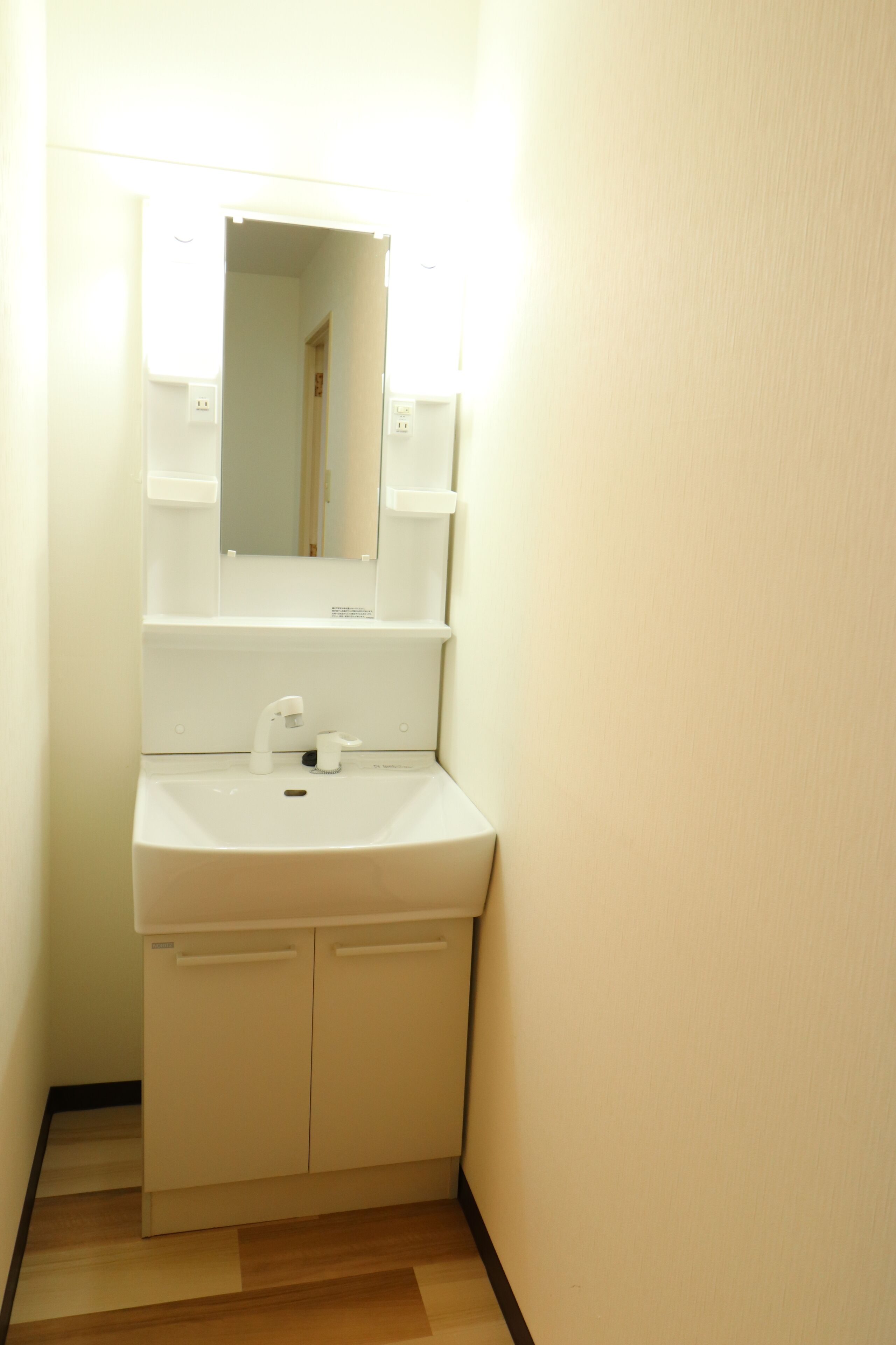 A small, white bathroom with a sink, mirror, and a door leading to another room.