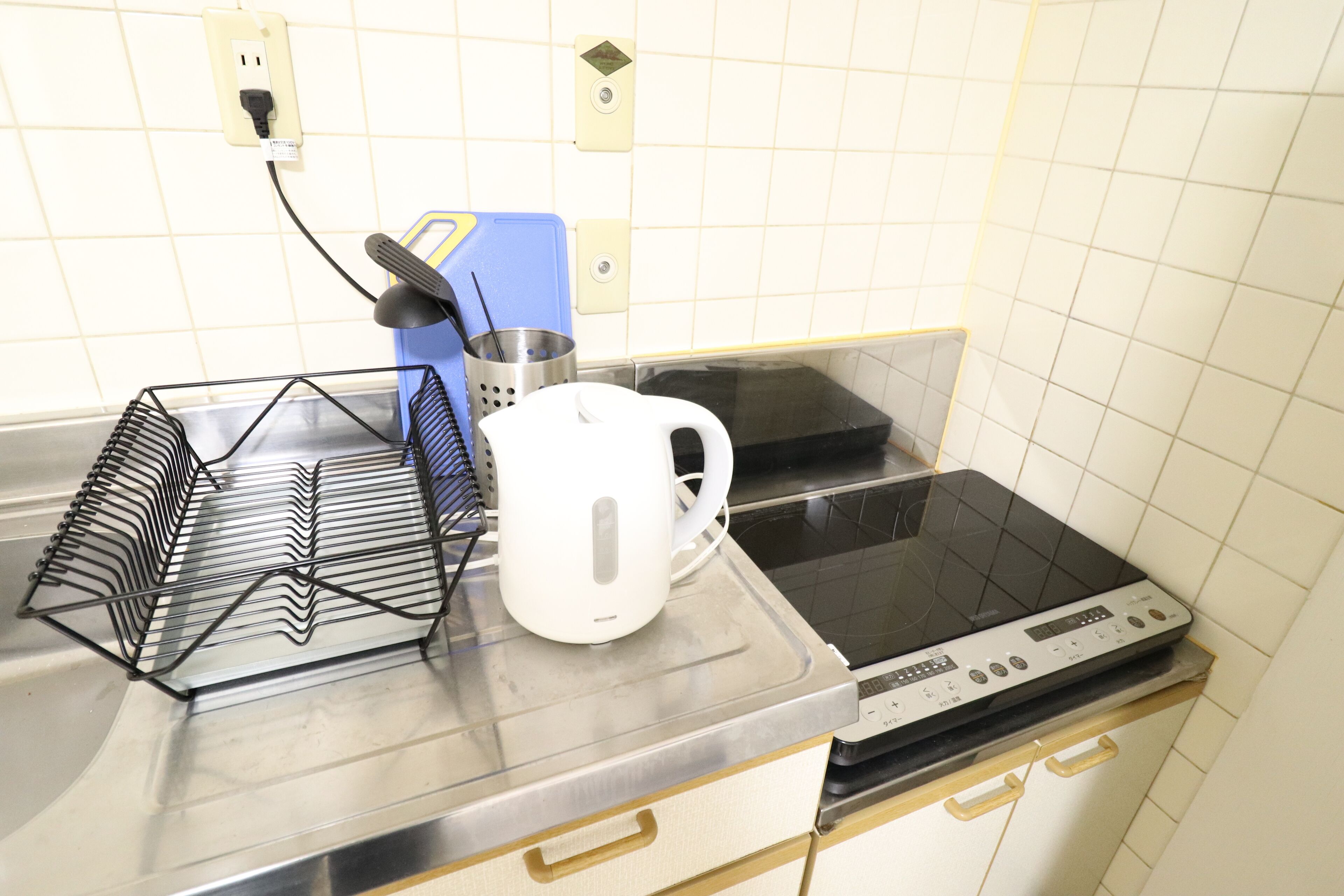 A kitchen with a microwave, a kettle, a coffee maker, and a power strip on the counter.