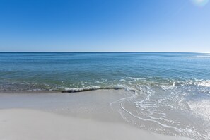 Een strand met helderblauw water en een zandstrand.