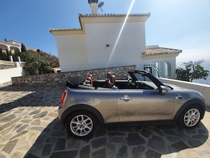 A silver convertible car parked on a stone-paved driveway.