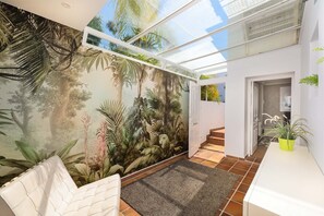 Ein modernes Interieur mit einem tropischen Wandgemälde, einer Glasdecke und einer Treppe zu einer weiteren Ebene.