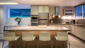 A modern kitchen with a central island, stainless steel appliances, and a view of a snowy landscape.