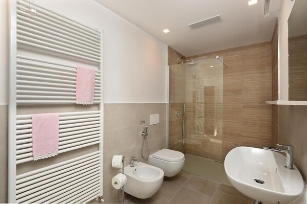 A modern bathroom with a shower, bidet, and sink.