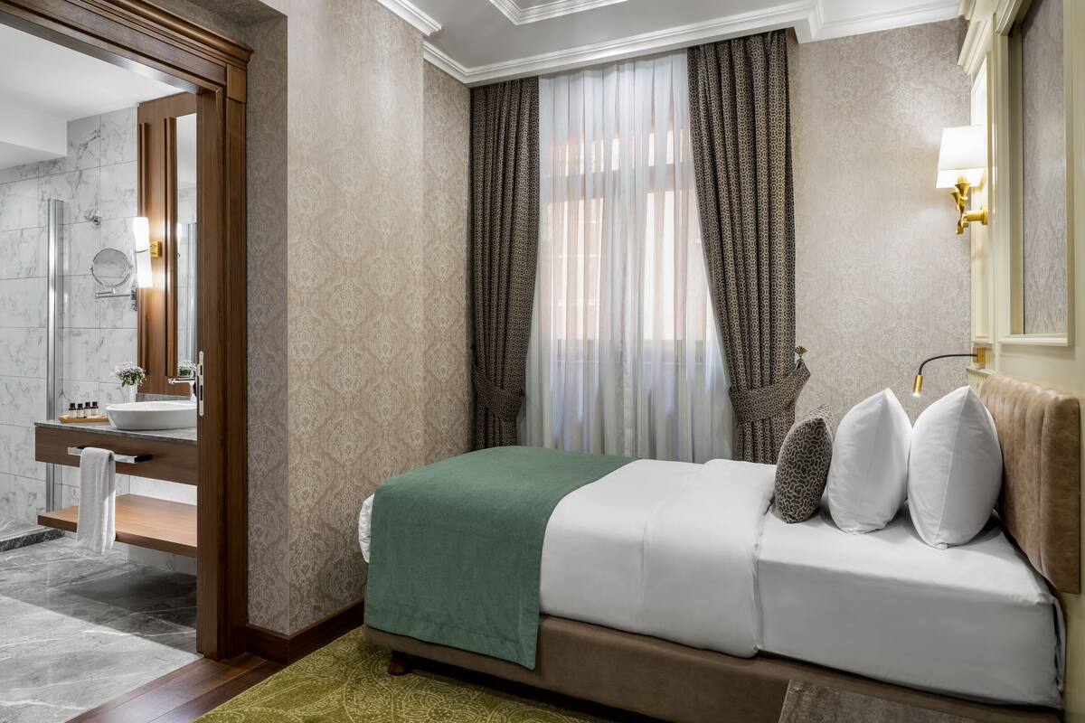 Una habitación de hotel con cama, baño con ducha, tocador y espejo.
