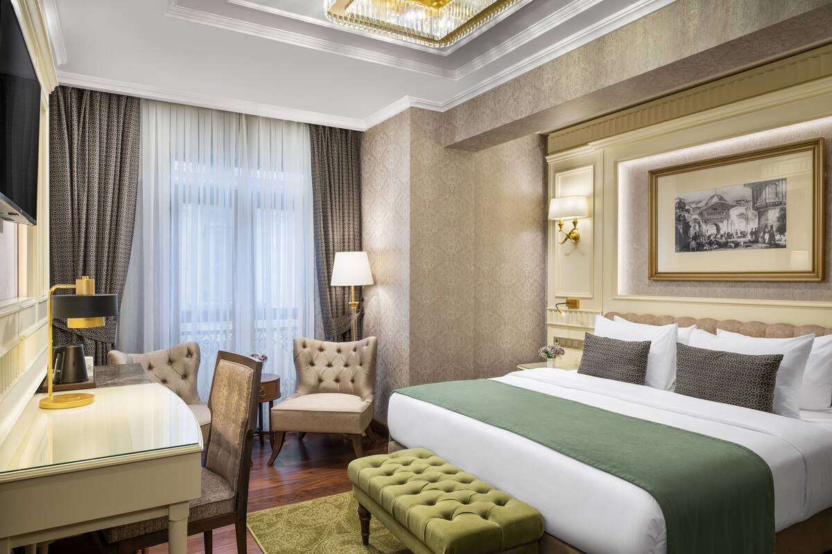 Una habitación de hotel con una cama grande, un escritorio, una silla y una lámpara.