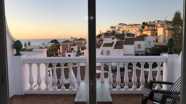 A balcony with a view of coastal buildings, a tiled floor, and outdoor furniture. - "Townhouse with Sea View" with Mountain View, Pool, Wi-Fi, Garden & Terrace (Nerja)