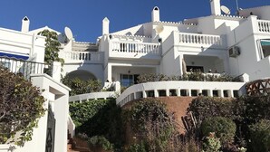 A white building with balconies, a staircase, and surrounding greenery. - "Townhouse with Sea View" with Mountain View, Pool, Wi-Fi, Garden & Terrace (Nerja)