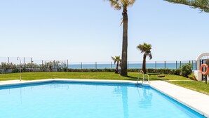 A swimming pool with a clear view of the ocean, surrounded by palm trees and a fence. - Charming Apartment with Sea Views & Wi-Fi (Mijas Costa)