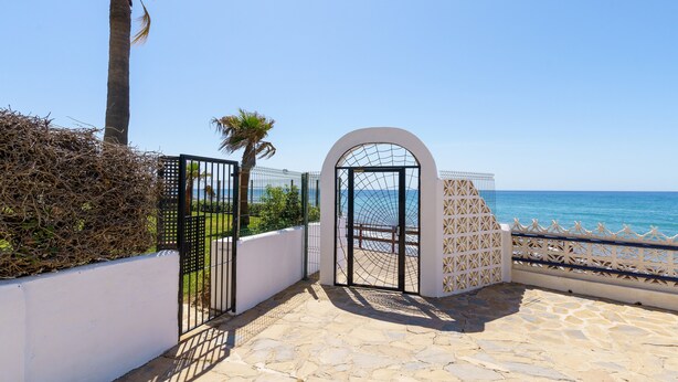 A gated entrance with a stone pathway leading to a beach view. - Charming Apartment with Sea Views & Wi-Fi (Mijas Costa)