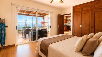 Et soveværelse med en stor seng, et træskab og udsigt til et udendørs område med et bord og stole.