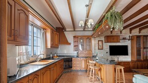 A spacious kitchen with wooden cabinets, a granite countertop, and a central island with stools. - Casa Tijoco – Large Terrace with Views of La Gomera, Air Conditioning, BBQ (Adeje)