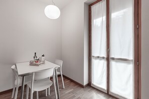 A dining area with a white table and chairs, a hanging light fixture, and a sliding glass door with curtains. - Lake Maggiore Retreat - Unique view, balcony, and private parking (Stresa (VB))