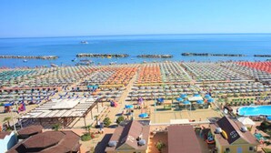 A beach with rows of umbrellas and sun loungers, a swimming pool, and a view of the sea. - Escape in Central Cattolica (Cattolica)