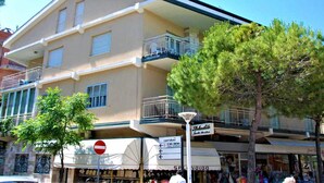 A multi-story building with balconies and a sign indicating a nearby restaurant. - Escape in Central Cattolica (Cattolica)