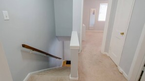 Una escalera que lleva a una habitación con una puerta blanca y un ventanal pequeño.