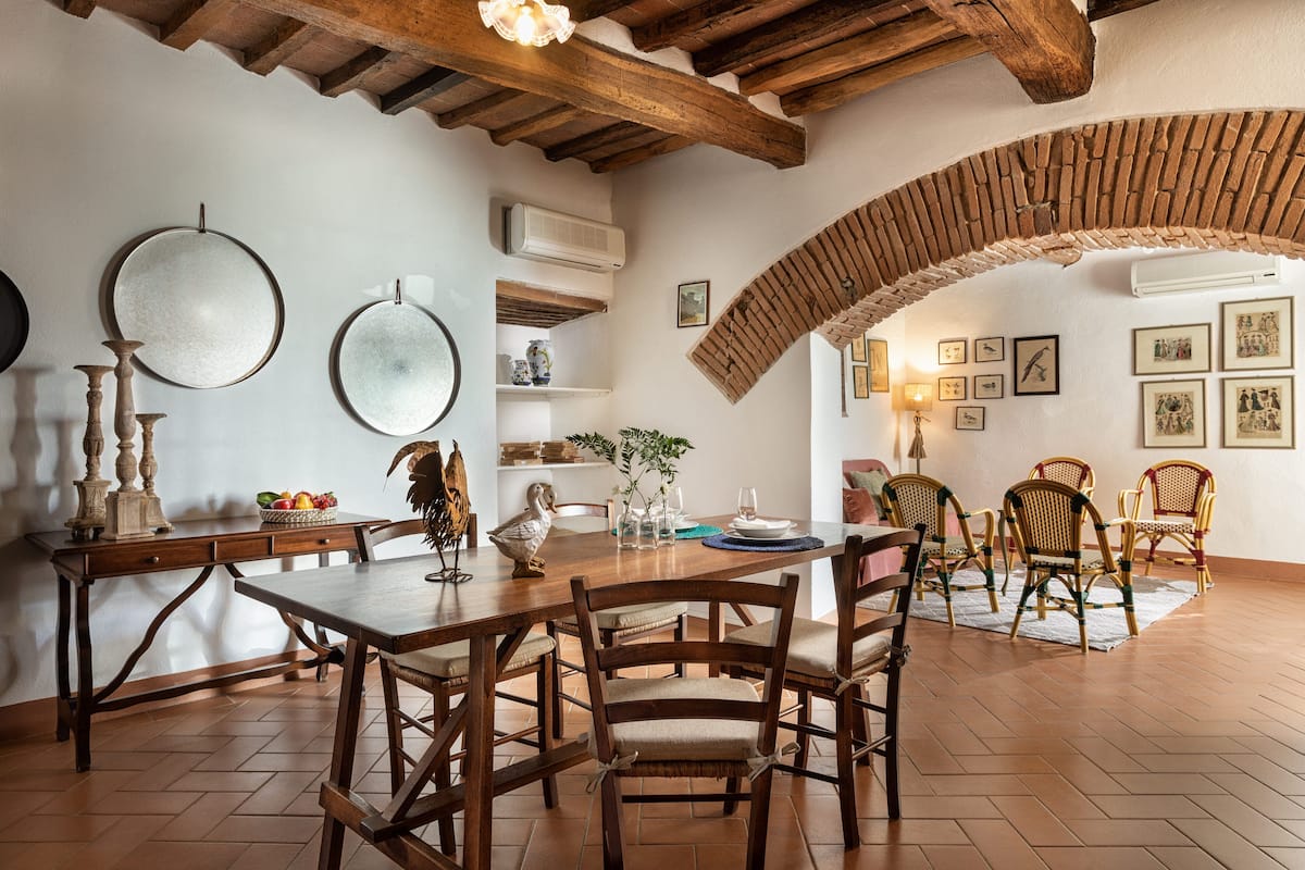 A dining area with a wooden table, chairs, and a rustic ceiling.