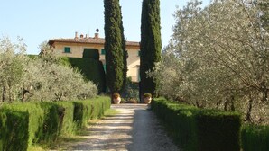 A gravel path leading to a building with a tiled roof and green shutters. - AGRITURISMO LA PAPESSA (Barberino Tavarnelle)