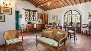 A spacious living area with a high wooden ceiling, wicker furniture, and a dining table set for four. - AGRITURISMO LA PAPESSA (Barberino Tavarnelle)