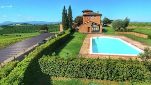 Una villa con piscina, rodeada de un césped cuidado y un viñedo.