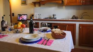 Una mesa de comedor servida con platos, vasos y un bol de fruta.