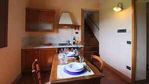 Una cocina compacta con armarios de madera, encimera de mármol y una mesa de comedor preparada para dos.