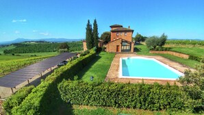 Una villa con piscina, rodeada de un viñedo y un conjunto de paneles solares.